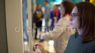 一位年轻女子在购物中心的触摸终端点菜。 现代技术。 在食品法庭上